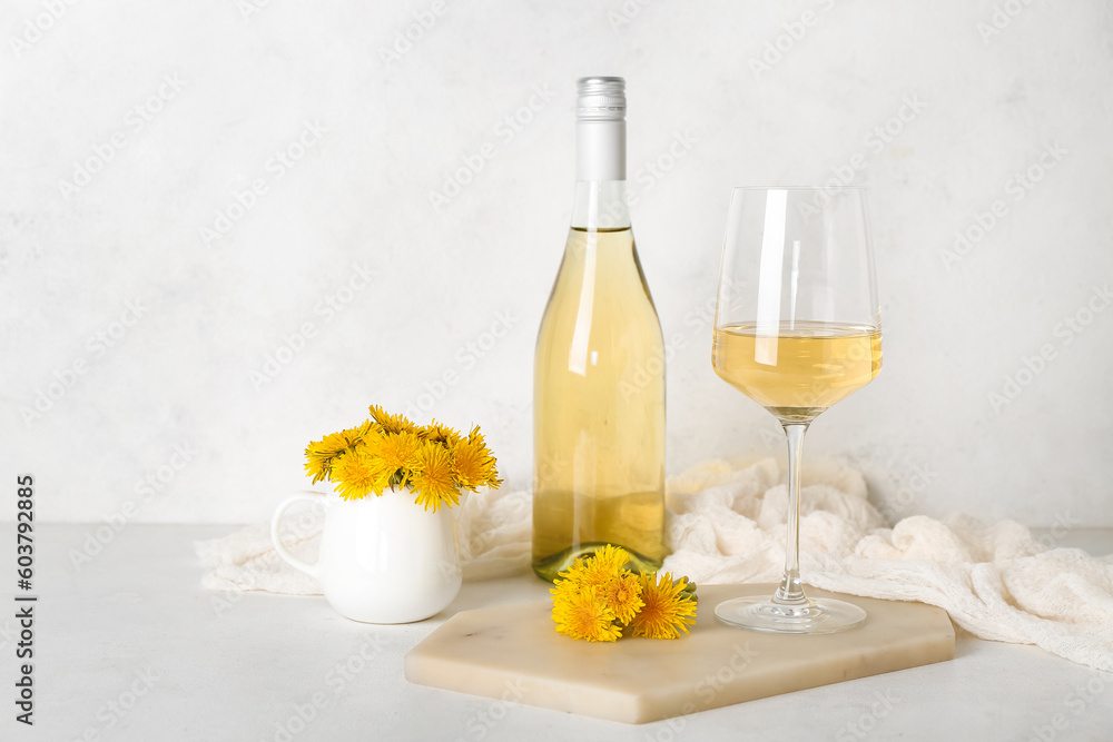 Bottle and glass of dandelion wine on white table Bottle and glass of dandelion wine on white table