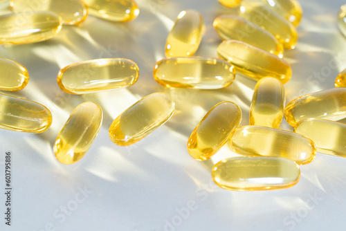 Fish Oil Omega 3 on white background, vitamin D yellow supplement gel capsules, macro shot
