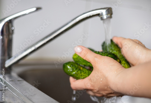 woman in kitchen analyse grocery from food market,hold check receipt in hand,calculating with phone.shocked amazed girl female about high prices,global crisis.hands wash cucumbers under water jet sink