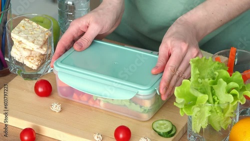 Close the lunch box with food, put a bottle of water and put an apple. Lunch is ready. Back to college concept. Beginning of the school year. Caring mother's hands