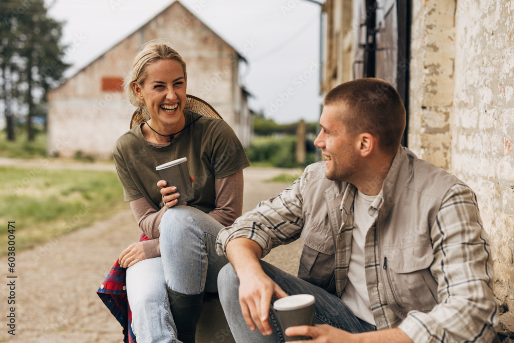 Obraz premium A woman and a man sit outside on the stairs and laugh while talking.