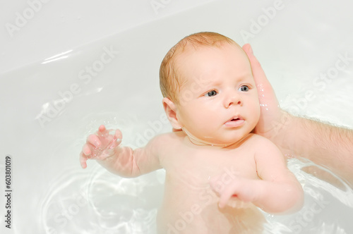 A young father bathes his newborn baby. Parenthood.