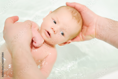 A young father bathes his newborn baby. Parenthood.