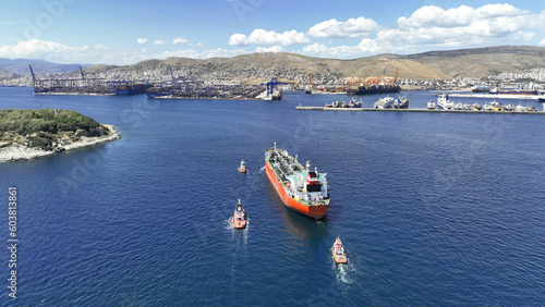 Aerial drone photo of huge crude oil tanker assisted by tug boats cruising near container terminal of Perama, Piraeus, Attica, Greece © aerial-drone