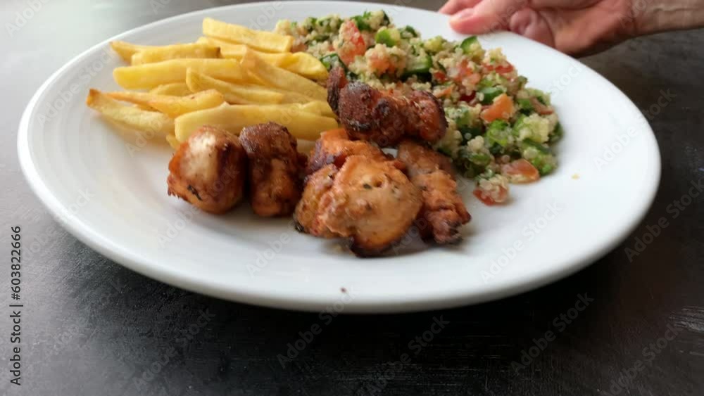Serving a Plate of Chicken Sis with French fries and Tabbouleh Serving a Plate of Chicken Sis with French fries and Tabbouleh