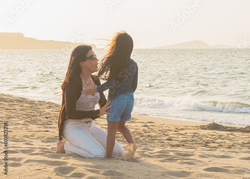 mom and 4 year old daughter on the beach in an idyllic sunset, Shot of a young woman spending time at the beach with her adorable daughter, Mother and daughter holding hands, running jumping on sunny 