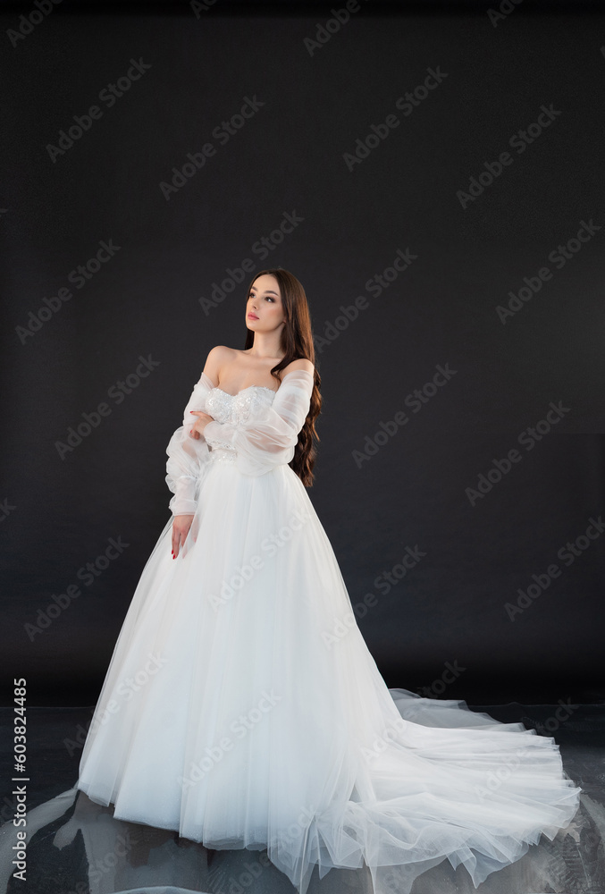 Fototapeta premium Beautiful fashion bride posing in wedding dress on black background 