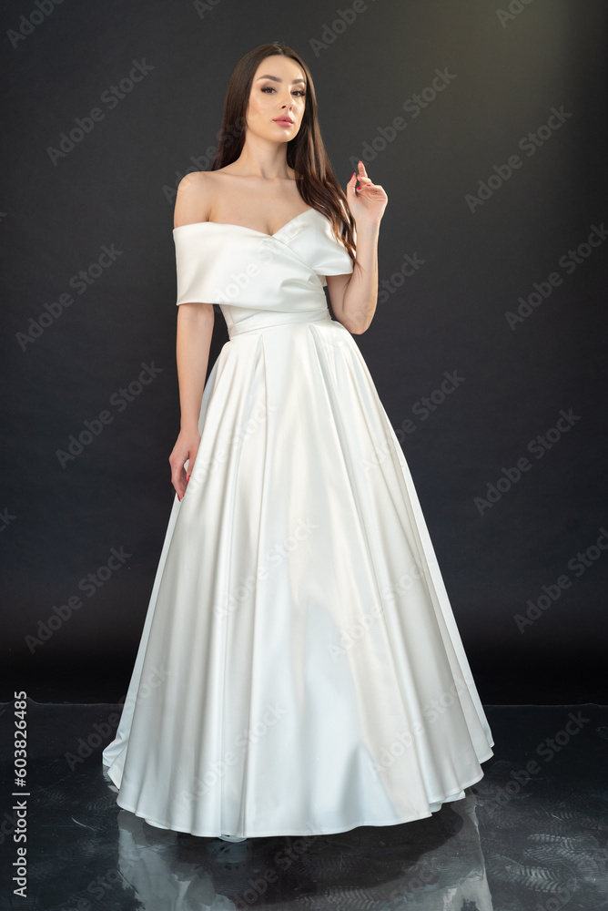 Fototapeta premium Stylish beautiful woman bride in wedding dress on black background