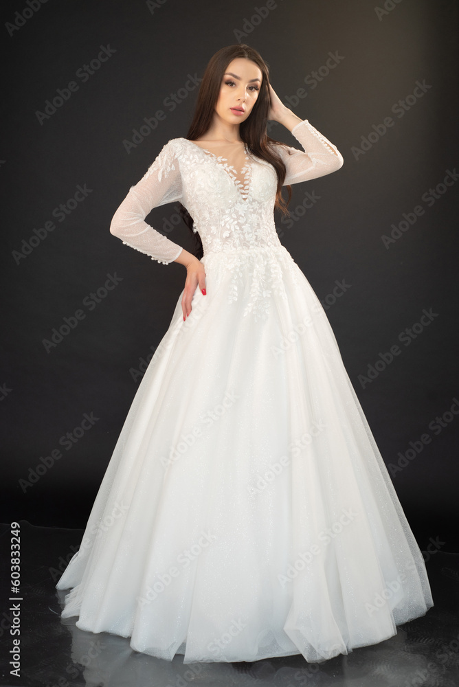 Beautiful fashion bride posing in wedding dress on black background Beautiful fashion bride posing in wedding dress on black background