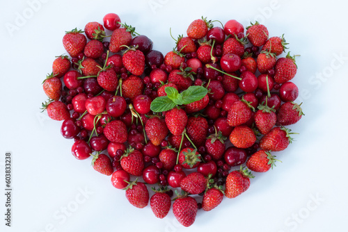 Strawberries and cherries in a heart shape isolated on white. Top table view. A close-up. Fresh organic spring and summer fruit harvest, love for plant-based food concept.