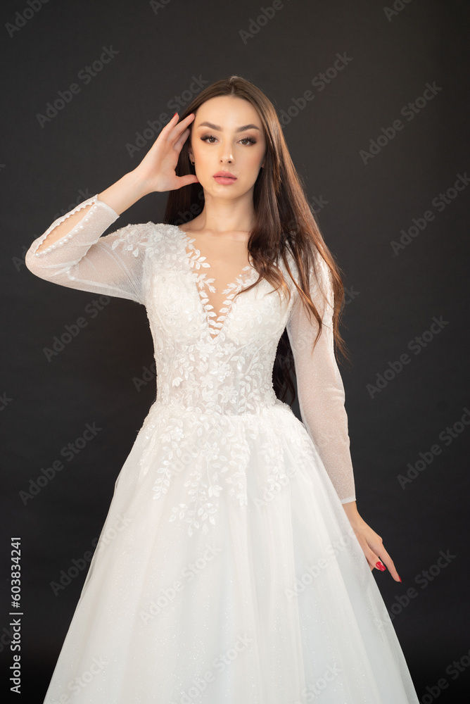 Beautiful fashion bride posing in wedding dress on black background Beautiful fashion bride posing in wedding dress on black background