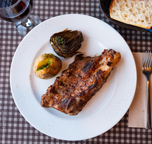 Appetizing baked pork ribs with whole potatoes and artichoke