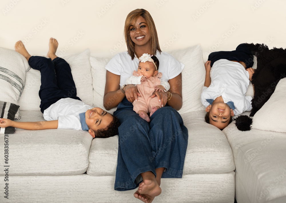 Beautiful African American woman sitting on couch with baby girl on her ...