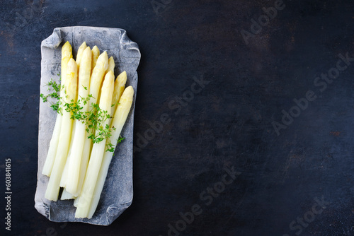 White asparagus glazed with cress served as top view on a design tray with text space right