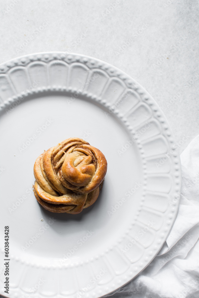 top view of Swedish cinnamon buns on a white plate, cinnamon twists on a plate, top view of homemade Kanelbullar top view of Swedish cinnamon buns on a white plate, cinnamon twists on a plate, top view of homemade Kanelbullar