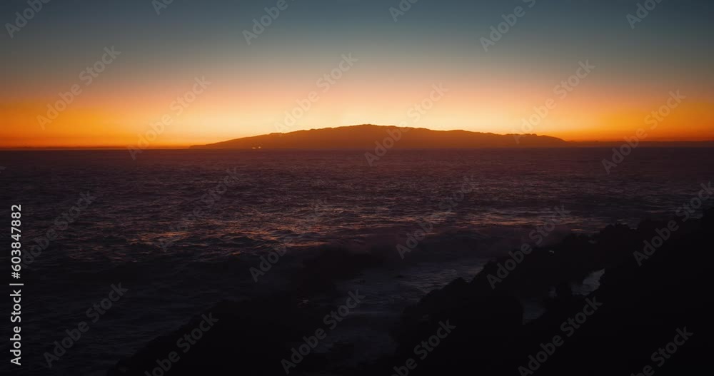 Majestic sunset light on sky with reflection on ocean surface. Scenic dark sea water waves close-up. Silhouette of Island La Gomera Canary Islands. Majestic sunset light on sky with reflection on ocean surface. Scenic dark sea water waves close-up. Silhouette of Island La Gomera Canary Islands.