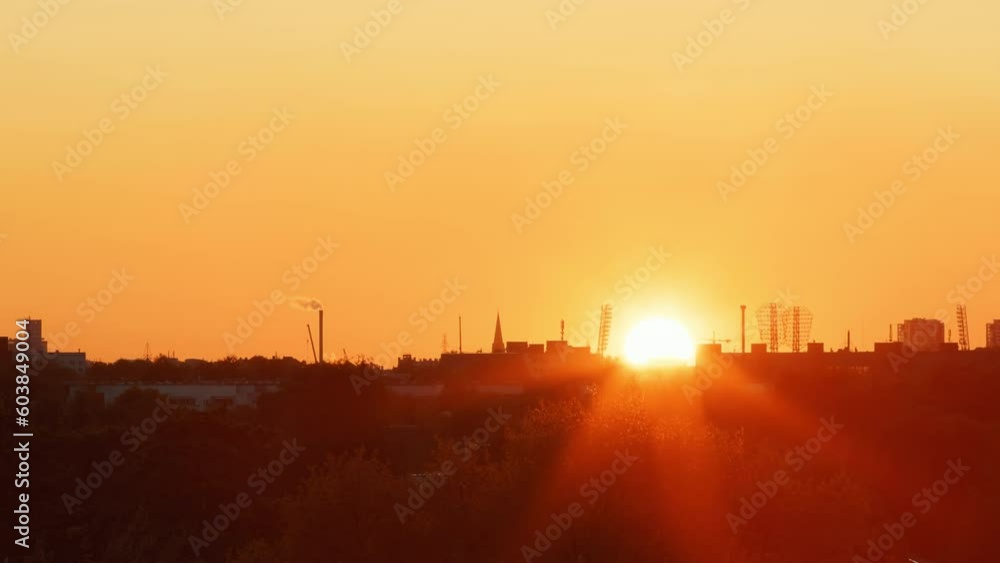 Vivid and Captivating Sunset: A Large Sun Setting Over a Clear Sky, Offering a Beautiful Contrast to the Darkened City Vivid and Captivating Sunset: A Large Sun Setting Over a Clear Sky, Offering a Beautiful Contrast to the Darkened City
