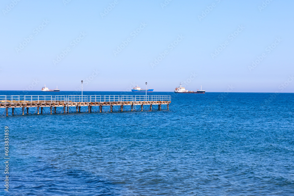 Long pier in the sea . Ships on the sea horizon 