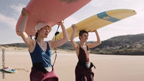 Young women carrying surfboards walking talking on ocean beach. Active surfer sports women friends couple getting ready to practice in the sea, catch a wave on a high tide.  photo