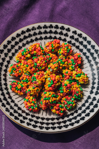 colorful clusters of candy on patterned black and white plate, purple background