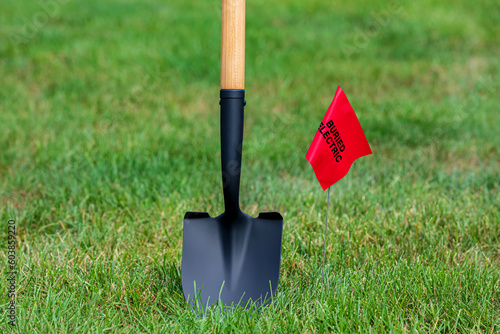 Fototapeta Buried electric line utility warning flag with shovel
