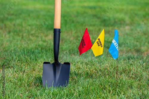 Buried electric, natural gas and water utility warning flag with shovel. Notify utility locate company for underground utilities, call before you dig and digging safety concept