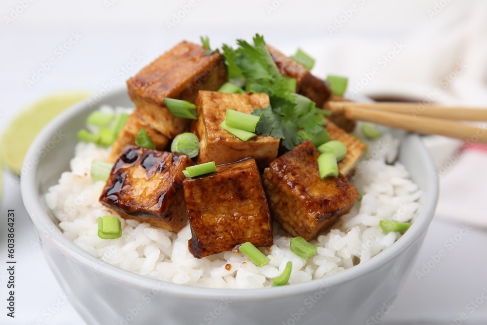Bowl of rice with fried tofu and greens on white table, closeup Bowl of rice with fried tofu and greens on white table, closeup