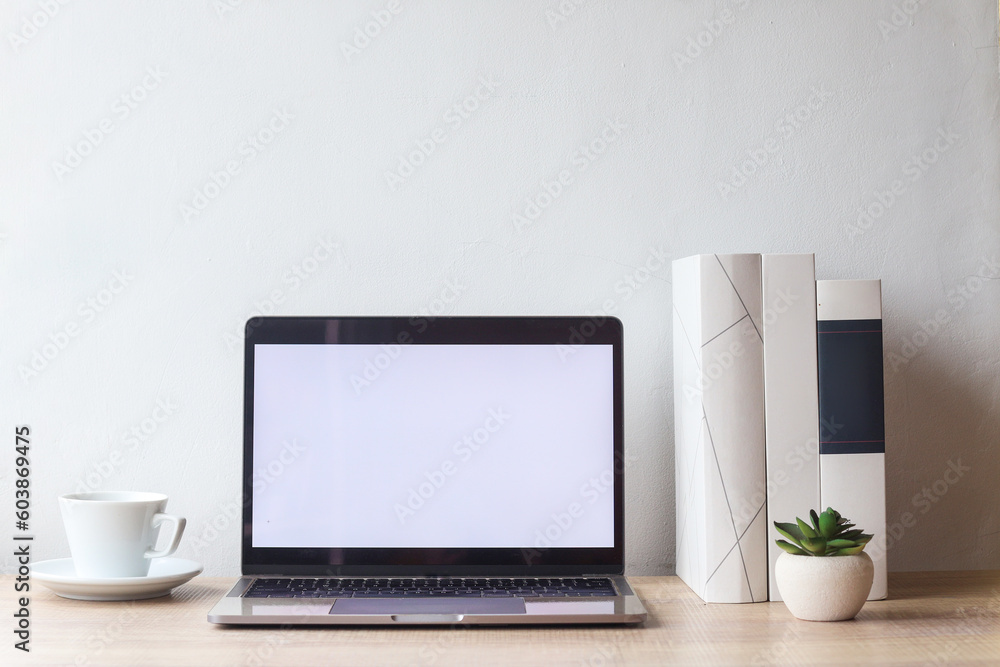 Comfortable workplace with open blank screen laptop computer, coffee cup, succulent and books on wooden desk Comfortable workplace with open blank screen laptop computer, coffee cup, succulent and books on wooden desk