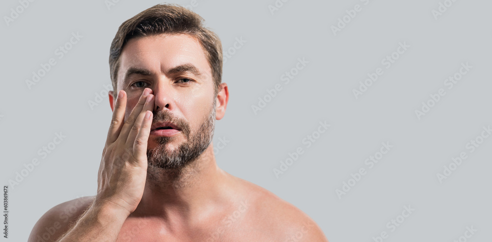 Fototapeta premium Close up beauty portrait of satisfied man after facial cream. Attractive brunet guy touching skin. Men model face with beard and modern haircut. Banner for header, copy space. Poster for web design.