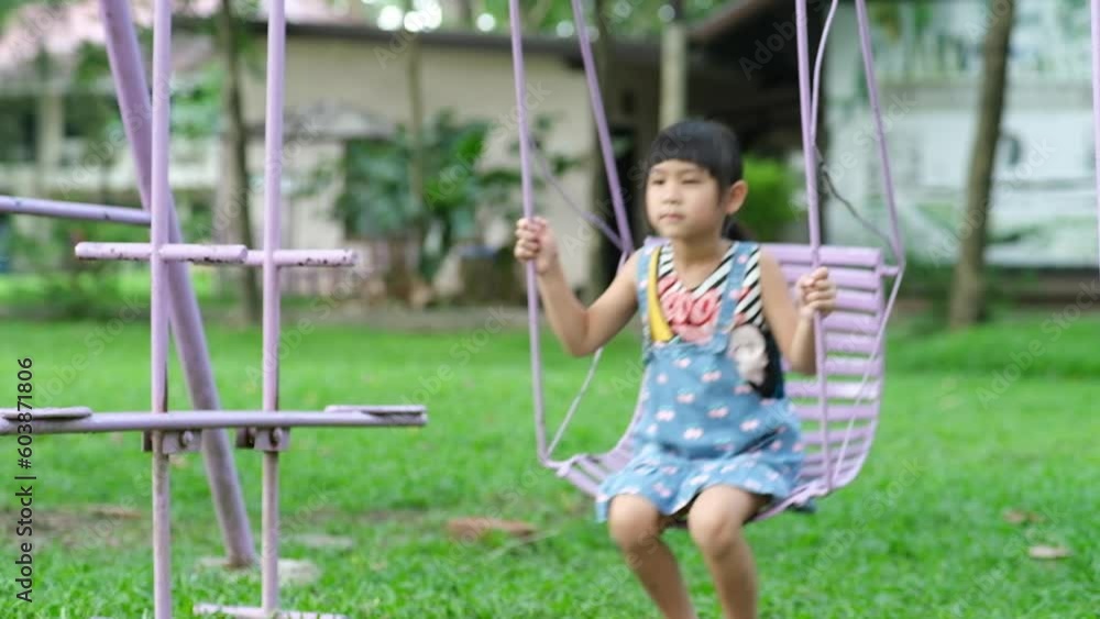 Happy Asian girl having fun playing in the playground during summer. Cute little girl swinging in the playground with a smile and laughter. Active summer leisure for kids. Happy Asian girl having fun playing in the playground during summer. Cute little girl swinging in the playground with a smile and laughter. Active summer leisure for kids.