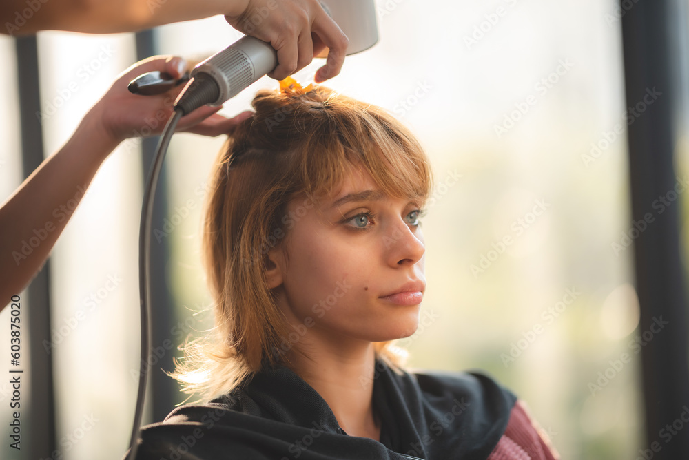 Fototapeta premium Asian Hairdresser giving treatment and barber occupation service, Professional hairstylist combing and using scissors cut woman's hair to young beautiful customer girl in beauty salon