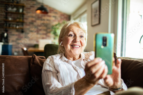 Senior woman using a smart phone while sitting on a Couch in a Living Room