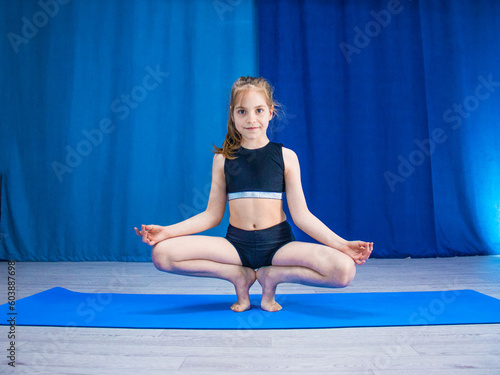 girl in a tracksuit is doing gymnastics, children's gymnastics, prapadasana, tiptoe pose