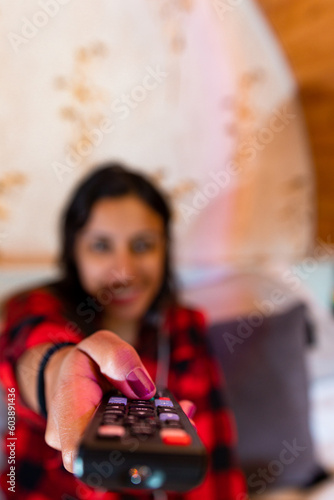 TV Entertainment Bliss: Woman Smiling while Flipping Channels with Remote