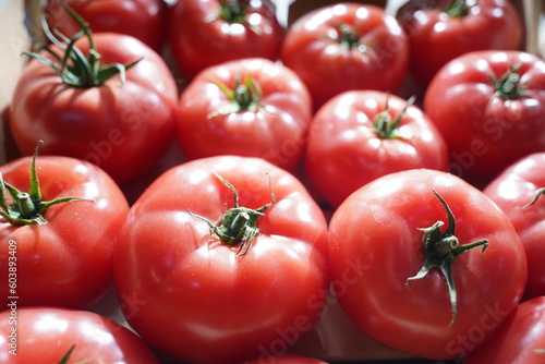 Fresh selected tomatoes in wooden boxes on sale.