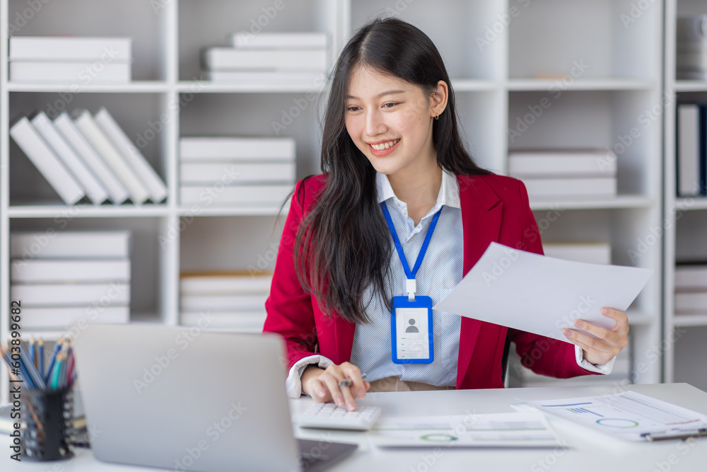 Asian Businesswoman Using laptop computer and working at office with calculator document on desk, doing planning analyzing the financial report, business plan investment, finance analysis concept. Asian Businesswoman Using laptop computer and working at office with calculator document on desk, doing planning analyzing the financial report, business plan investment, finance analysis concept.