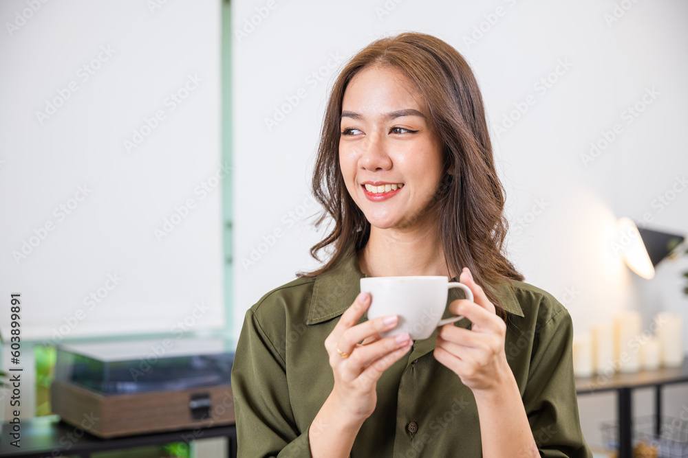 Portrait of Happy beautiful woman rest in summer after wakeup at office room, Asian young woman hands holding hot coffee or tea cup for drink in morning while posing, white porcelain mug mock up Portrait of Happy beautiful woman rest in summer after wakeup at office room, Asian young woman hands holding hot coffee or tea cup for drink in morning while posing, white porcelain mug mock up