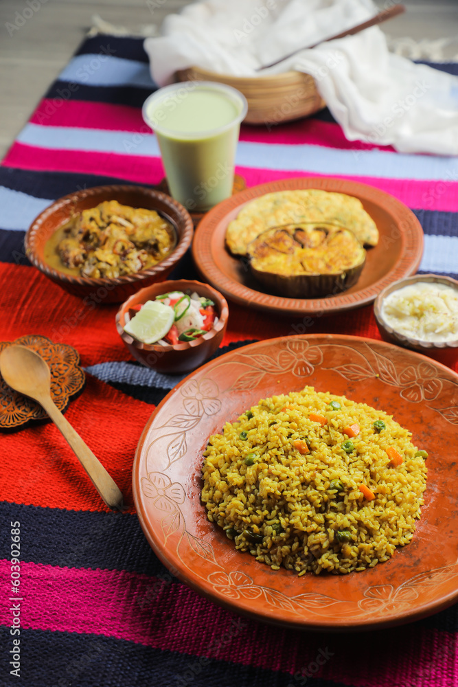 Achari Chicken Khichuri Combo with egg plant and omelet, borhani, salad and Chui Pitha served in dish isolated on mat top view of indian and bangladeshi food Achari Chicken Khichuri Combo with egg plant and omelet, borhani, salad and Chui Pitha served in dish isolated on mat top view of indian and bangladeshi food