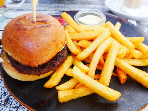 Obraz na płótnie Burger with french fries on wooden table. Hamburger with golden fries served with mayonnaise and ketchup. High-calorie and high-fat fast food. Unhealthy food w salonie
