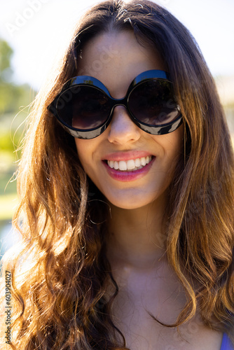 Portrait of happy fit caucasian woman wearing sunglasses smiling in sunny garden