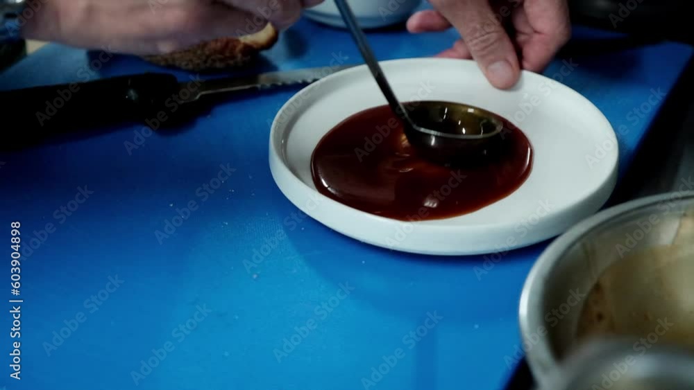 Chef applies melted caramel to a plate with a ladle before serving Chef applies melted caramel to a plate with a ladle before serving
