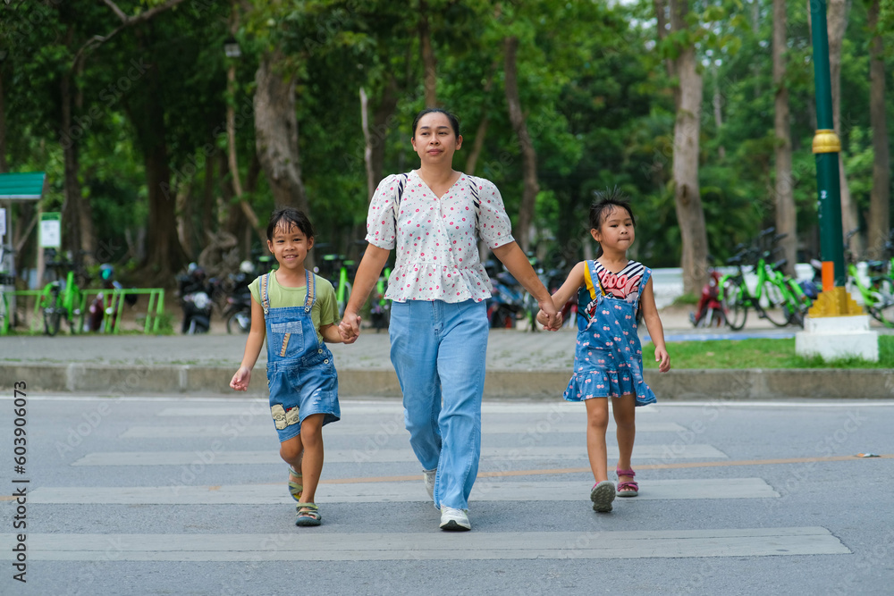 Mother and children holding hands cross the road on the crosswalk. Road traffic safety concept. Mother and children holding hands cross the road on the crosswalk. Road traffic safety concept.