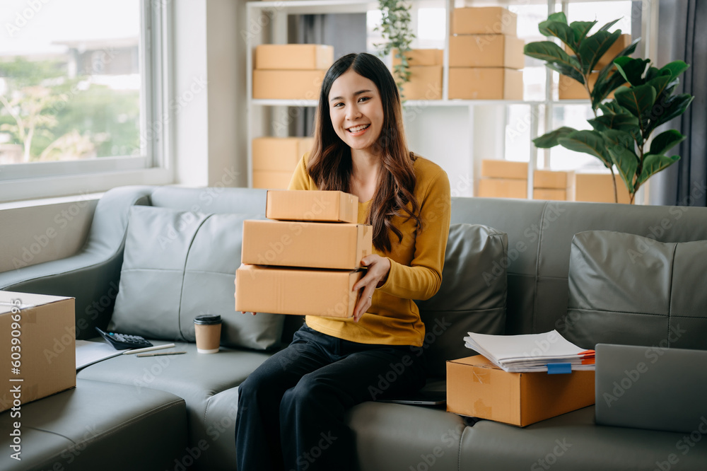 Young asian business owner woman prepare parcel box and standing check online orders for deliver to customer on tablet, laptop Shopping Online concept.. Young asian business owner woman prepare parcel box and standing check online orders for deliver to customer on tablet, laptop Shopping Online concept..