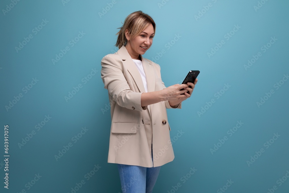 blonde young woman in a jacket makes a payment using a phone on a studio background blonde young woman in a jacket makes a payment using a phone on a studio background
