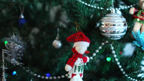 The hands of a child decorating an artificial Christmas tree with a toy in the form of a snowman. The atmosphere of preparation for the holiday.