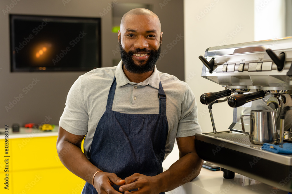 Portrait of bearded african american male barista in apron standing by coffee maker at coffee shop Portrait of bearded african american male barista in apron standing by coffee maker at coffee shop