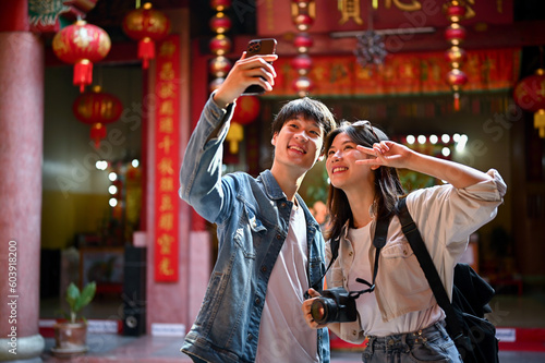Photo Cute Asian tourist couple taking their pictures with a smartphone while visiting