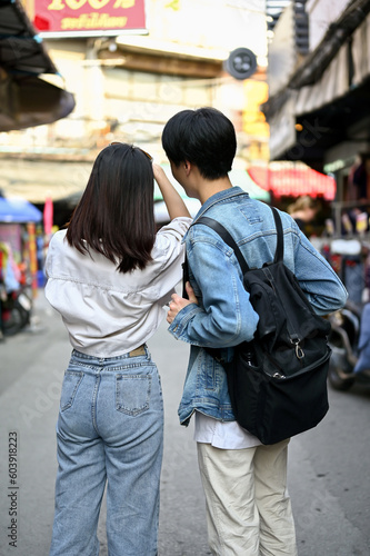 A tourist couple enjoys taking photos and sightseeing the old town market together.