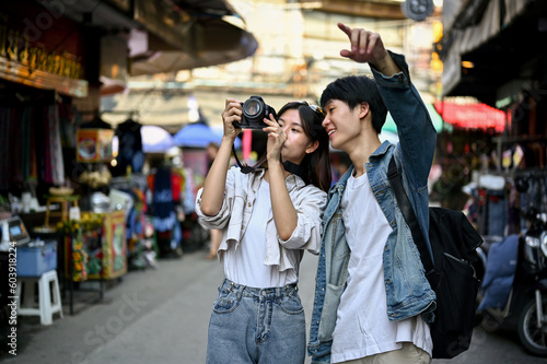 Young Asian tourist couple enjoys taking photos while sightseeing the old town city © bongkarn