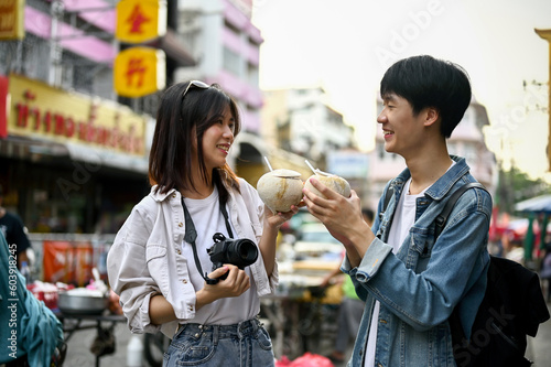 A tourist couple enjoying their fresh coconut drink while sightseeing in a Chinatown